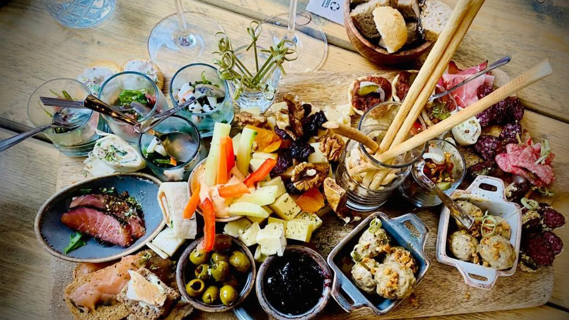 Vielfalt an Speisen und Snacks auf einer Holzplatte mit Wein und Gläsern