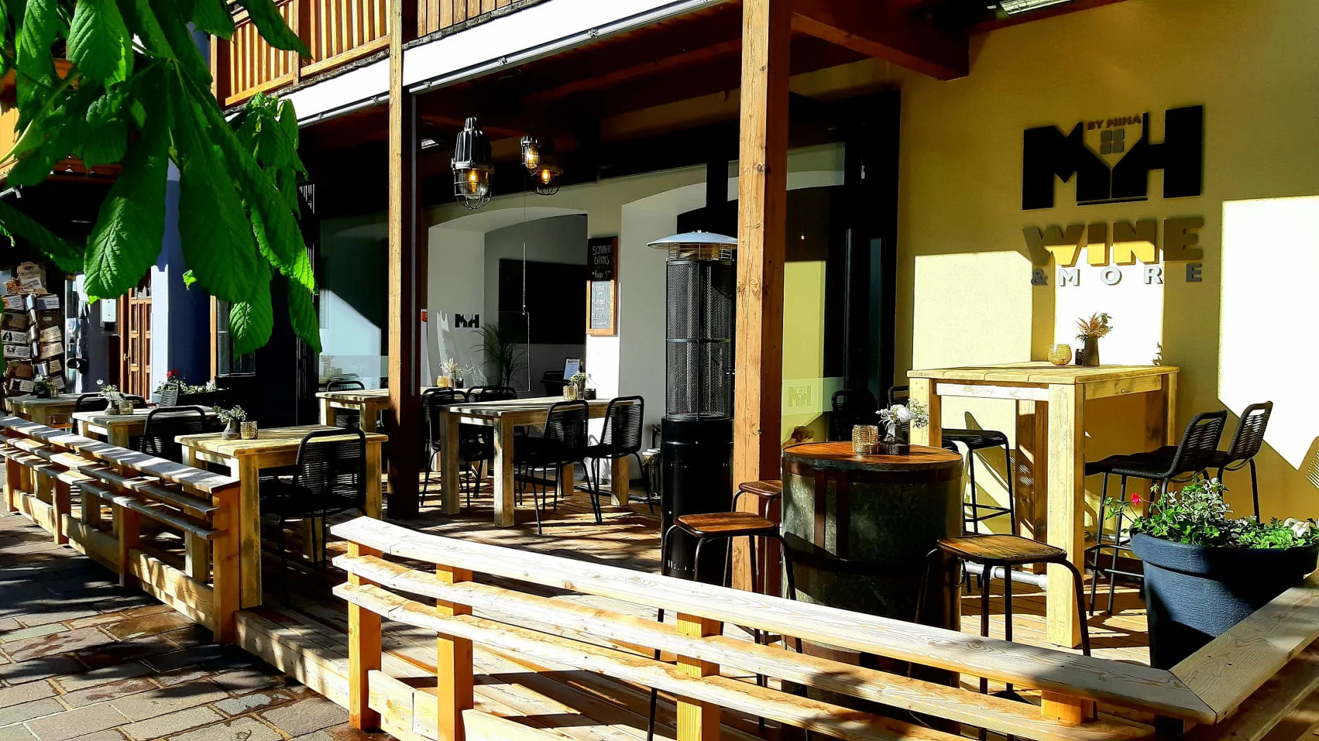 Terrasse mit Tischen und Stühlen, das Logo von Wine & More sichtbar