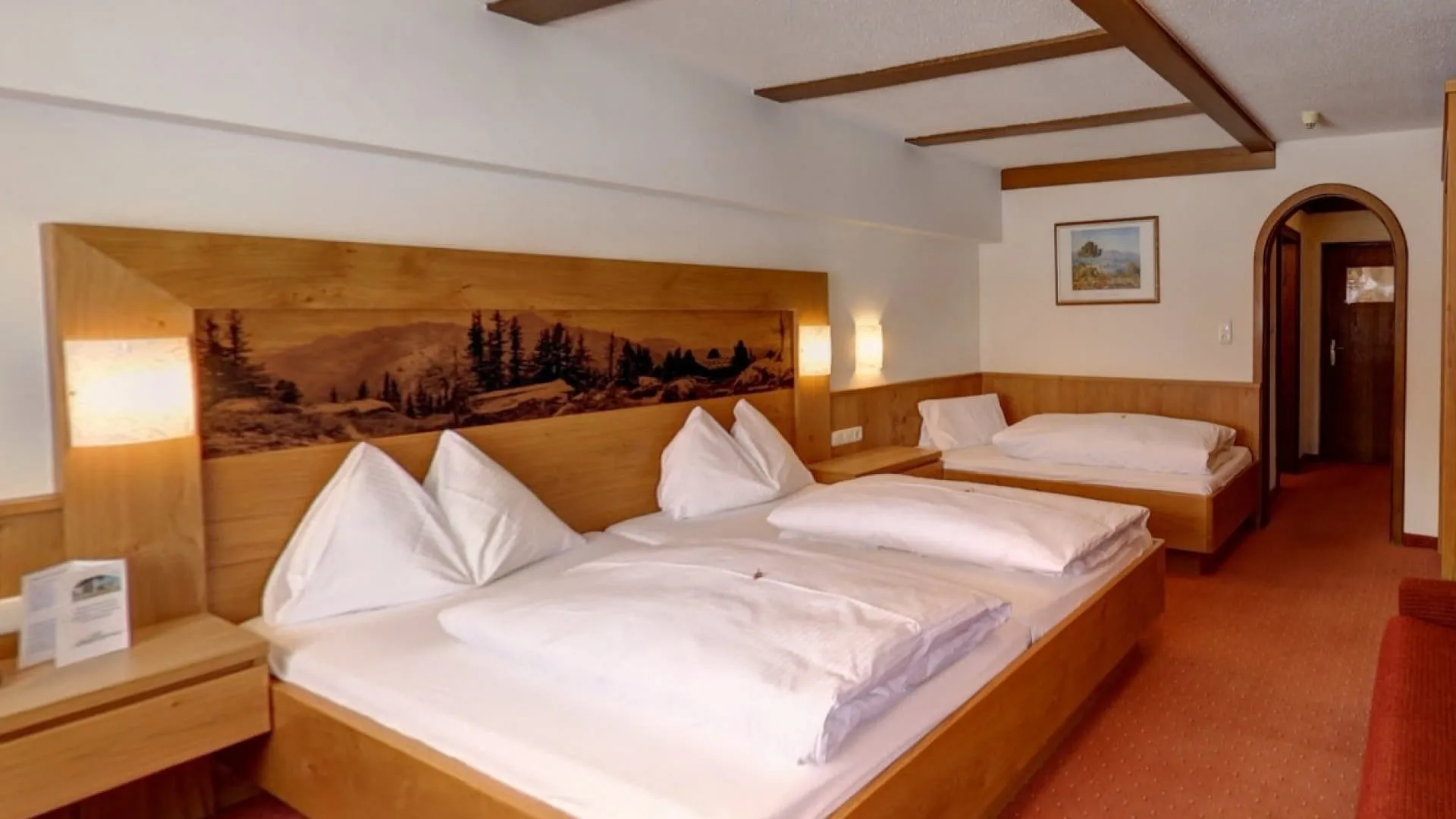 Helles Zimmer mit drei Betten und Holzdekor, warme Farben und angenehmes Ambiente